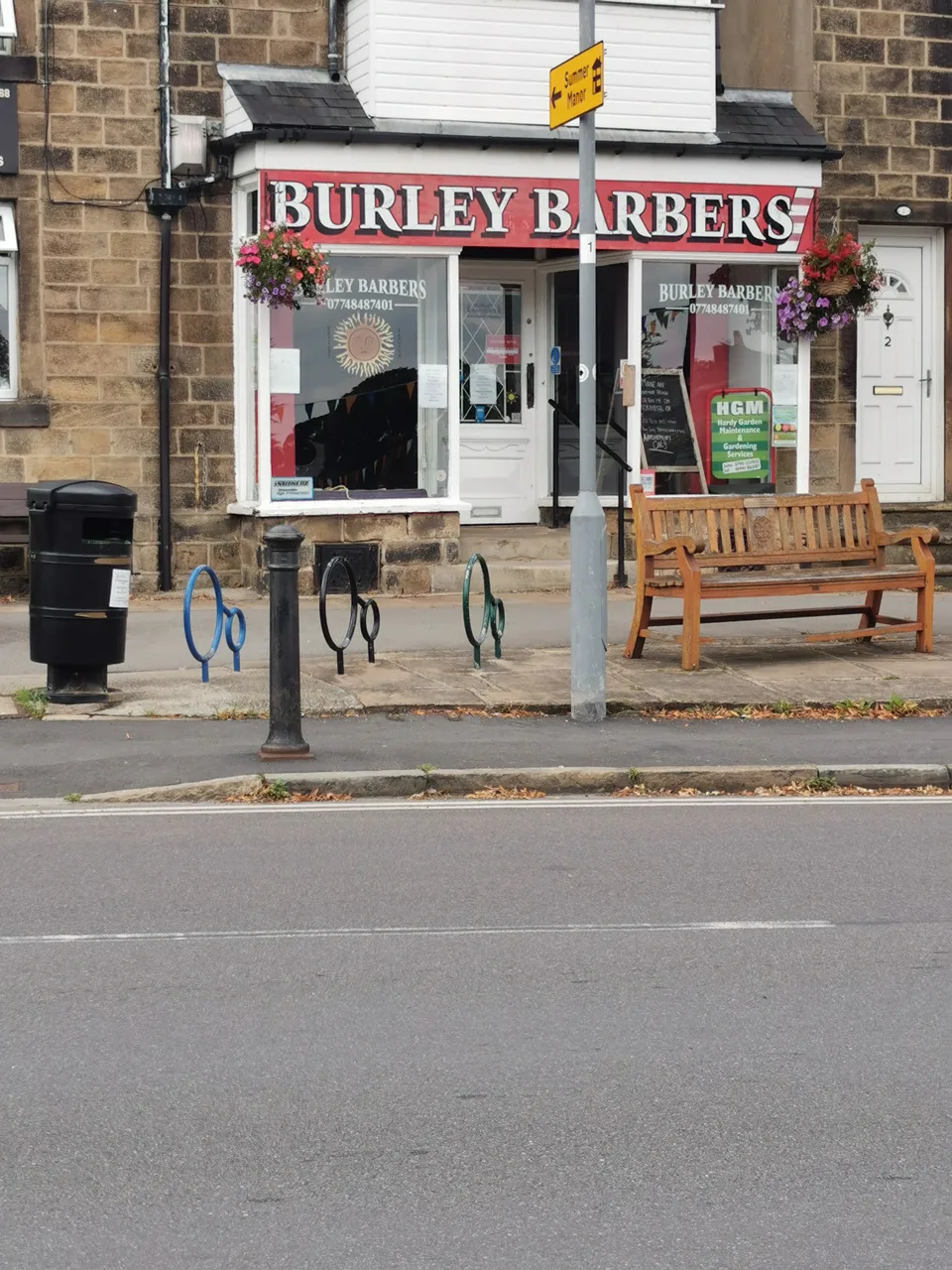 Burley Barbers on Station Road, with hanging baskets and a bench outside